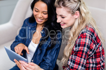 Young woman showing digital tablet to female friend