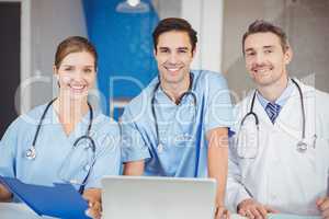 Portrait of cheerful doctors with laptop and clipboard