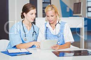 Female doctors using digital tablet while sitting at desk