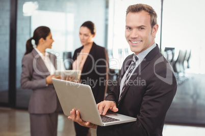 Portrait of businessman holding laptop in the office