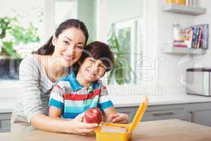 Portrait of smiling mother and son with lunch box