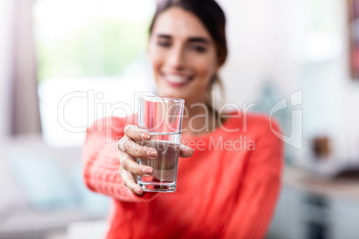 Young woman showing drinking glass with water