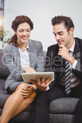 Smiling business professionals using digital tablet