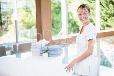 Female masseur rolling towel on massage table