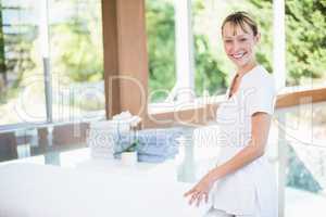 Female masseur rolling towel on massage table