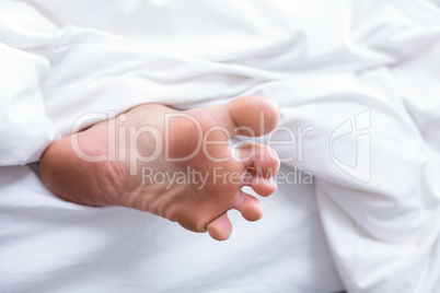Close-up of human foot on bed