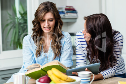 Female friends discussing while holding book and digital tablet Female friends discussing while holding book and digital tablet