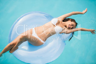 Young woman relaxing on swim ring at swimming pool
