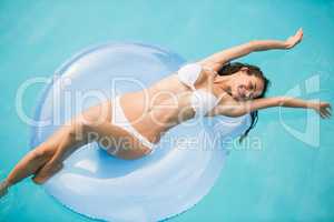 Young woman relaxing on swim ring at swimming pool