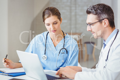 Male doctor with colleague working on laptop