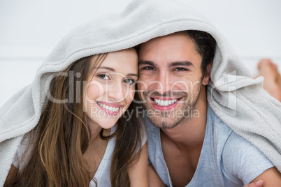 Portrait of smiling couple under blanket