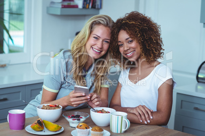 Smiling female friends sitting at breakfast table