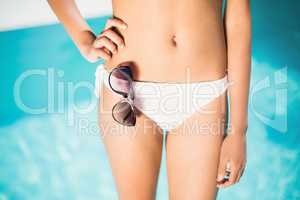 Mid section of a woman in white bikini standing near pool