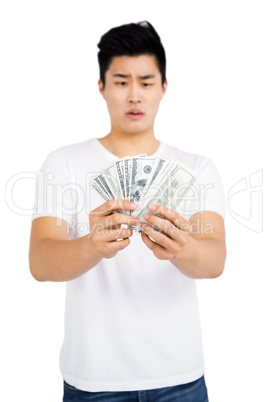 Upset young man counting fanned out currency notes