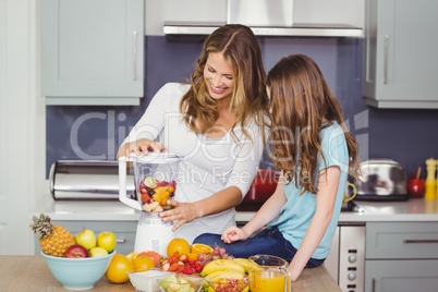 Happy mother and daughter preparing fruit juice
