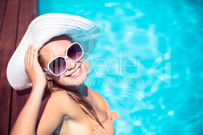 Beautiful woman wearing sunglasses and straw hat leaning on wood