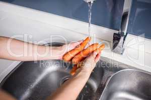 Woman washing carrots at kitchen sink