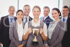 Winning business team with an executive holding trophy