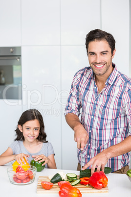 Portrait of smiling father cutting zucchini with daughter