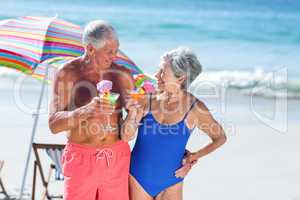 Cute mature couple having cocktails on the beach