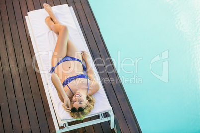 Beautiful woman in blue bikini lying on sun lounger