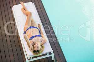 Beautiful woman in blue bikini lying on sun lounger