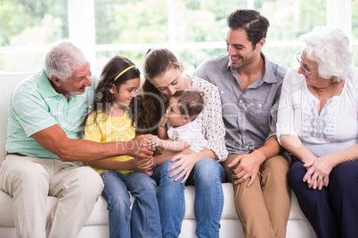 Smiling family playing with baby while sitting on sofa