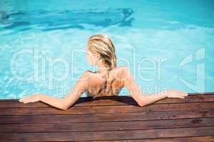 Beautiful woman leaning on wooden deck by poolside