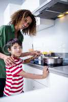 Portrait of mother and son cooking in kitchen