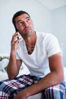 Man sitting on bed talking on phone