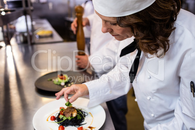 Female chef garnishing meal on counter