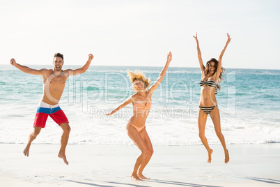 Beautiful excited friends jumping on the beach