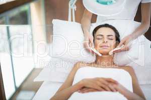 Young woman with eyes closed while receiving facial massage