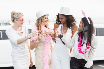 Frivolous women drinking champagne next to a limousine