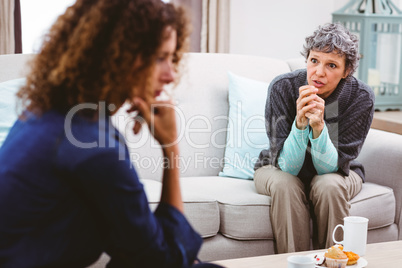 Upset mother discussing with daughter while sitting on sofa