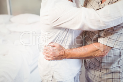 Midsection of senior man embracing wife