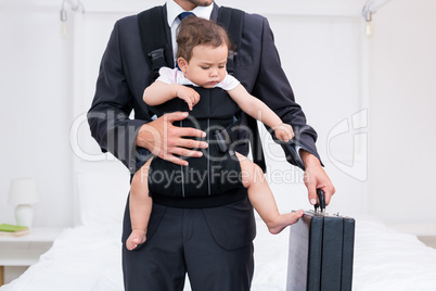 Midsection of father carrying baby while holding briefcase