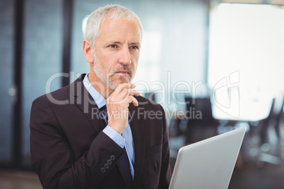 Businessman thinking while working on laptop
