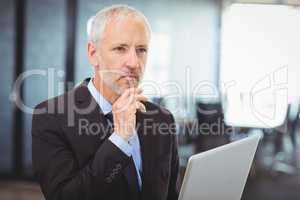 Businessman thinking while working on laptop