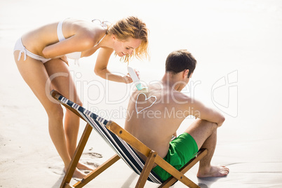 Woman making a heart symbol on mans back while applying a sunscr