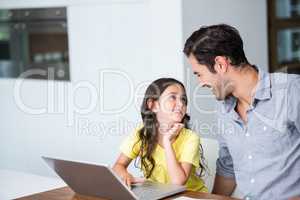 Smiling daughter using laptop