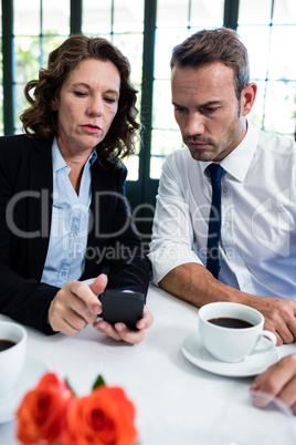 Business colleagues looking at mobile phone while having a meeti