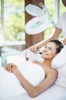 Happy young woman receiving facial massage