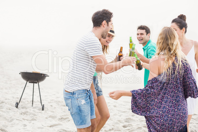 Group of friends dancing on the beach with beer bottles