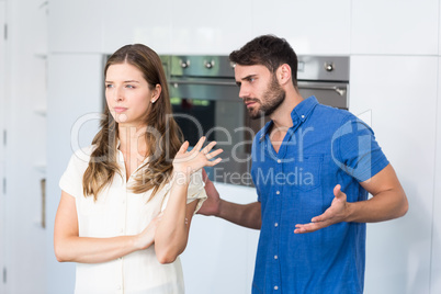 Man explaining to upset wife in kitchen