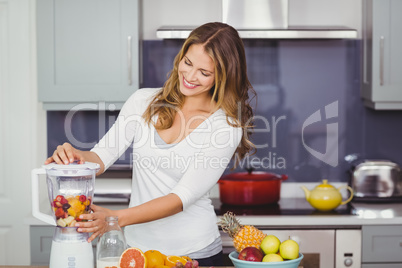 Smiling young woman using juicer