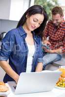 Couple using laptop and digital tablet in the kitchen