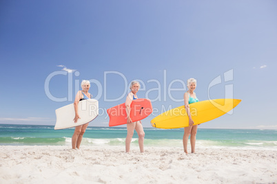 Senior woman friends holding surfboard