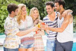 Group of friends toasting glasses of juice near pool