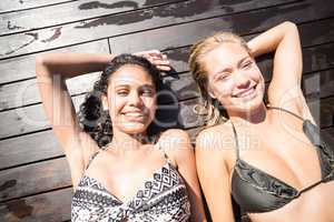 Two women in bikini relaxing on wooden deck